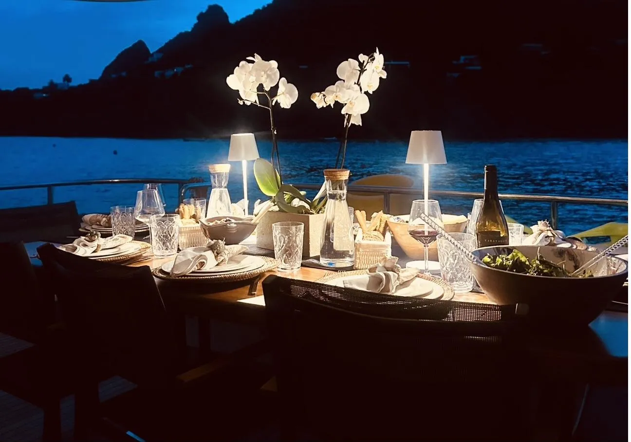 The table laid for dinner on the aft deck at night, lamps lit