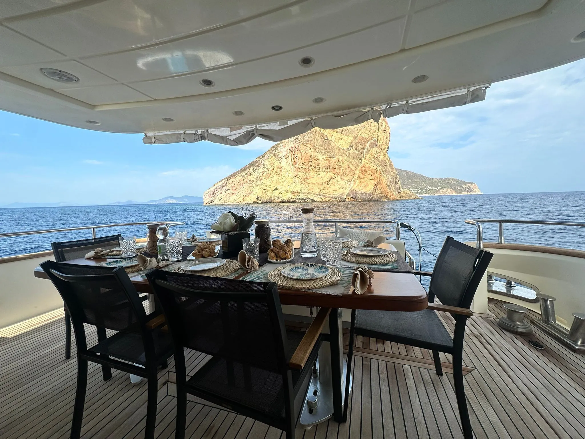 Breakfast laid out on the aft deck, the rock of Dattilo beyond