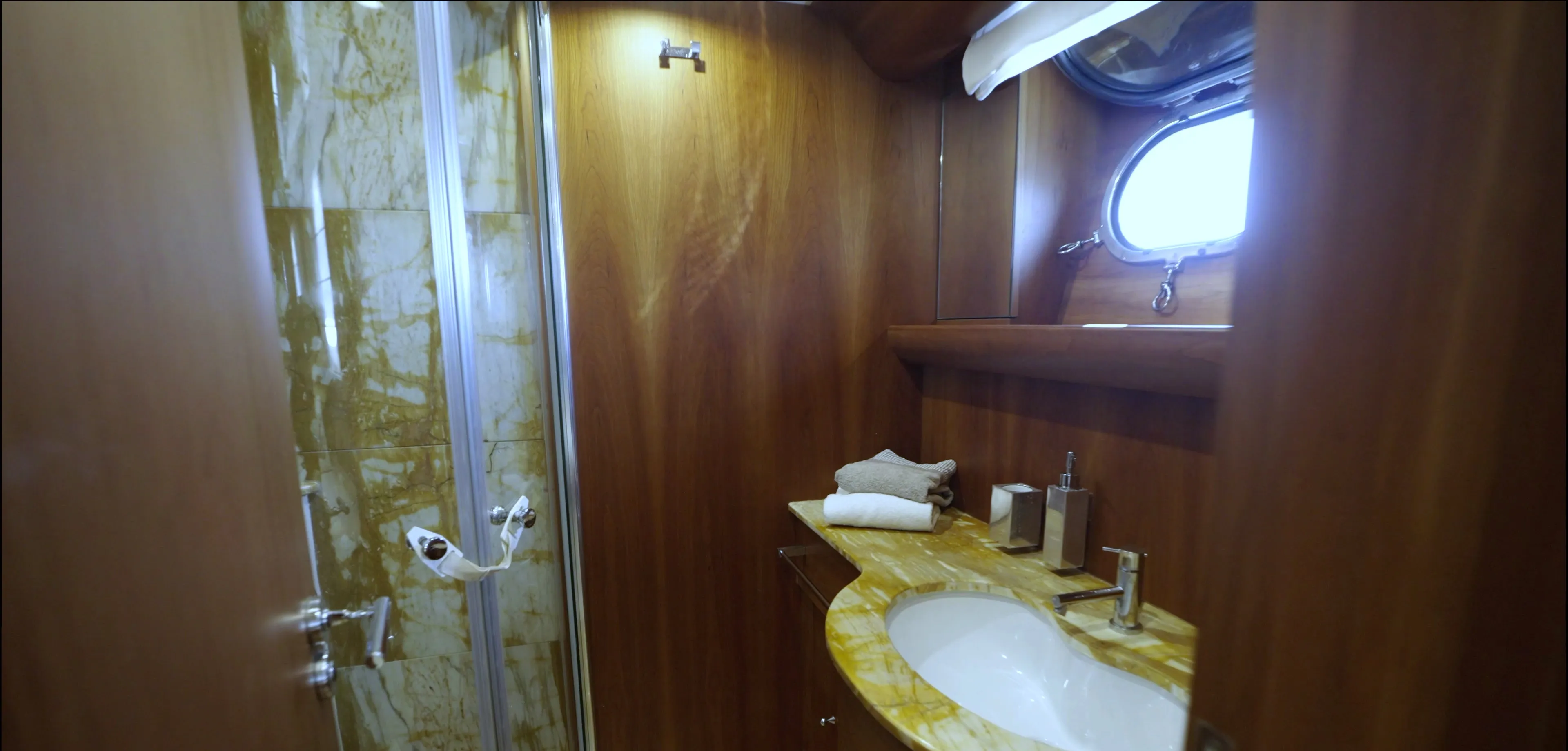 An en-suite bathroom: glazed shower cubicle, marble top, basin and porthole
